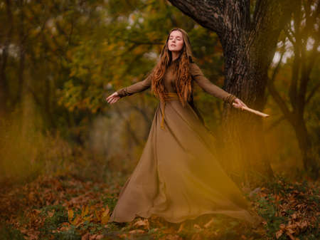 Redhead woman in dress walking in fantasy fairy tale forestの写真素材