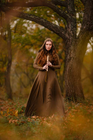 Redhead woman in dress walking in fantasy fairy tale forestの写真素材