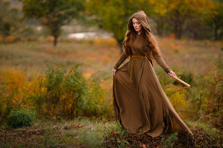 Redhead woman in dress walking in fantasy fairy tale forestの写真素材