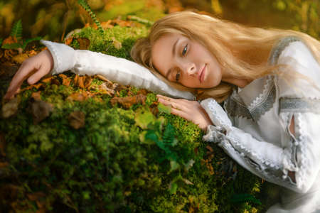 Beautiful young woman in a white dress in the middle of a forest