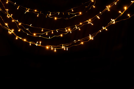 Abstract Christmas lights on black background. Glowing light bulb garland,の写真素材