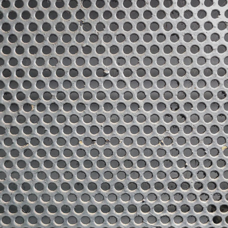 Close-up of a gray-painted perforated metal mesh with evenly spaced circular holes. Industrial texture suitable for backgrounds, design elements, or engineering-related themes.の写真素材