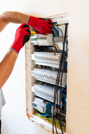 Electrician performing maintenance or installation work inside an electrical panel, ensuring safety...