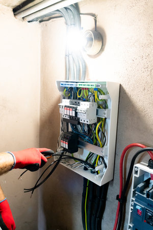 Electrician performing maintenance or installation work inside an electrical panel, ensuring safety and proper electrical connection.の写真素材