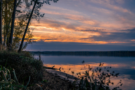 Peaceful sunset over Sulejow Bay in Poland, with golden light reflecting on calm water and...