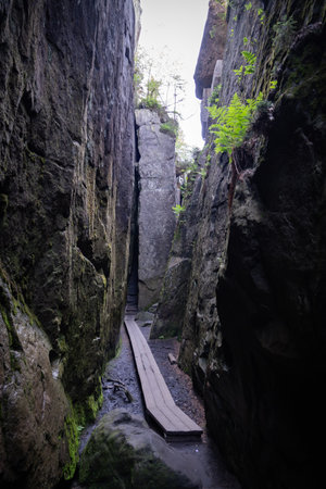 Narrow hiking trail carved between vertical sandstone rocks on Szczeliniec Wielki mountain in Poland. Natural corridor in the Stolowe Mountains.の写真素材