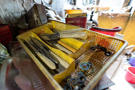 Several dirty knives lying in a plastic cutlery drainer, designed for drying utensils after washing....