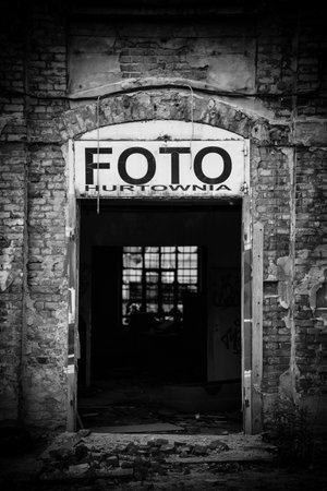 Black and white photograph of an abandoned building entrance without a door. A large sign with the text is visible above the entrance.の写真素材