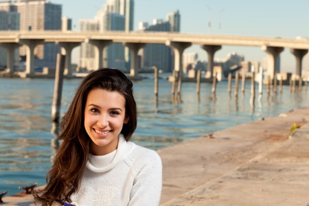 Pretty young woman in winter clothing along the bay at sunset の写真素材