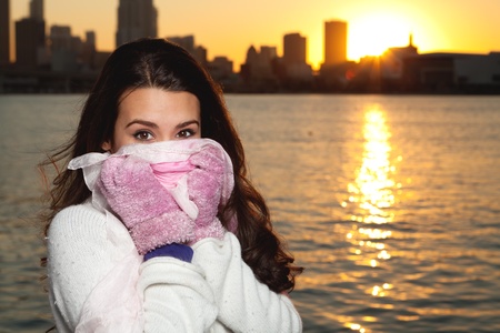 Pretty young woman in winter clothing along the bay at sunset の写真素材