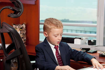 Cute boy in business attire in an officeの写真素材