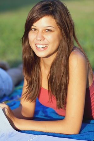 Pretty female college student studying on a campus fieldの写真素材