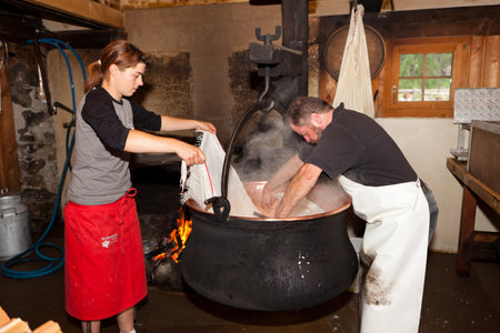 Swiss man and woman making cheese in a farm house