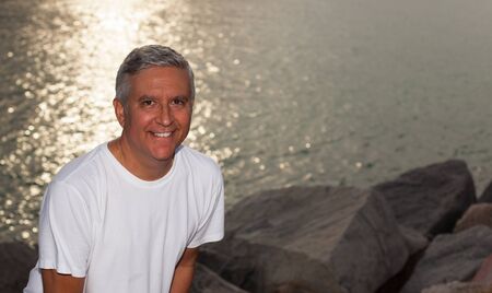 Handsome middle age man in casual clothing enjoying a park setting at sunset の写真素材