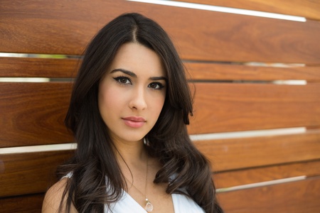 Beautiful young multicultural woman outdoors with a wooden background の写真素材