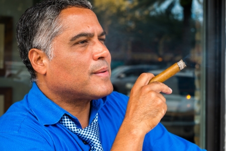 Handsome middle age Hispanic man smoking a cigar.の写真素材