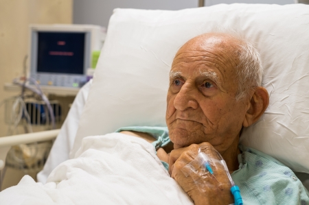 Elderly 80 plus year old man recovering from surgery in a hospital bed