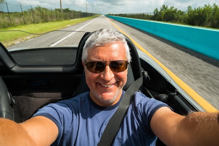 Handsome middle age man driving a convertible automobile on the highway の写真素材