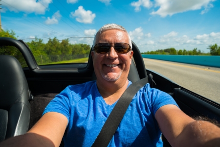 Handsome middle age man driving a convertible automobile on the highway の写真素材