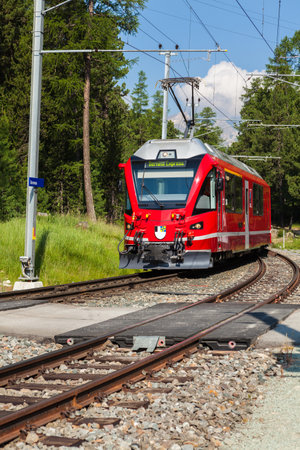 Swiss commuter train approaching a station in the Pontresina area of Switzerland