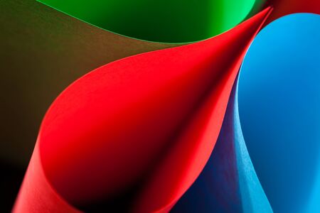 Colorful card stock in unique elliptical shapes with shadow effect and selective focus on a black background.の写真素材