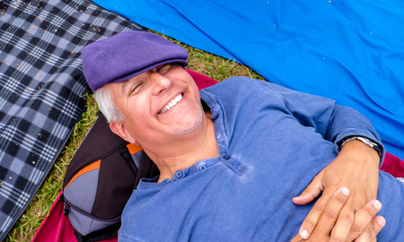 Handsome middle age man lying down outdoors with a funny expression.の写真素材
