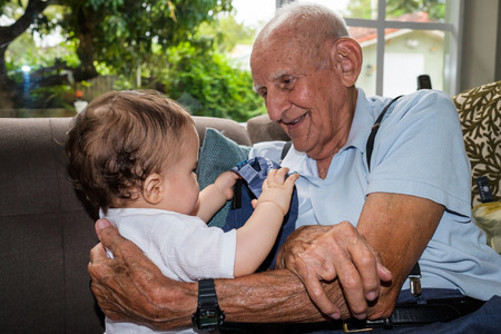 Cute baby boy with great grandfather in a home setting.の写真素材