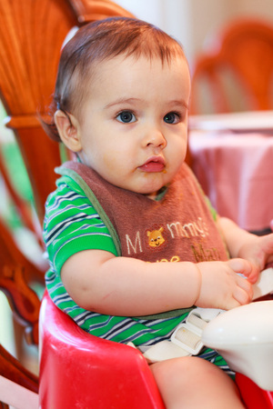 Hungry baby boy being fed a meal in a home setting.の写真素材