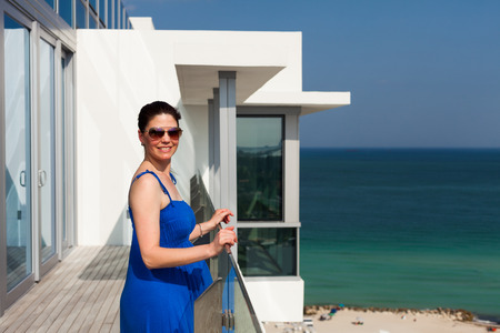 Beautiful middle age woman enjoying the sights of Miami Beach from a balcony.の写真素材