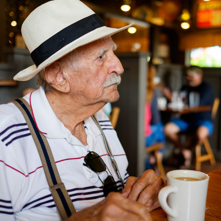 Elderly eighty plus year old man wearing a hat in a restaurant setting.の写真素材