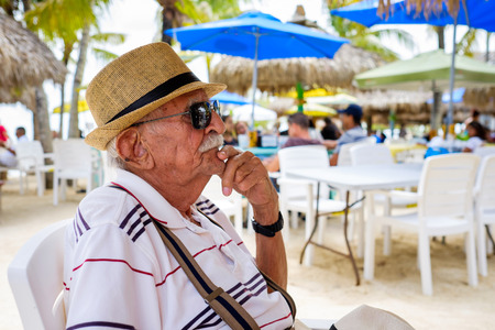 Elderly eighty plus year old man wearing a hat in a outdoor restaurant setting.の写真素材