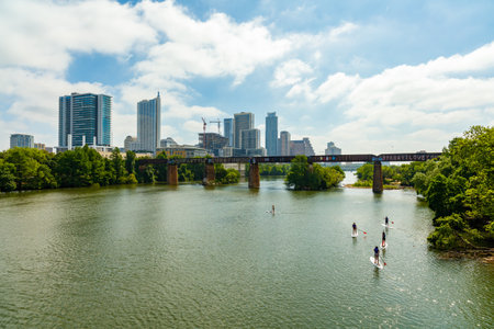 Austin, TX USA - April 14: Skyline view of the downtown area along the Colorado River with paddle boarders cruising by.のeditorial素材