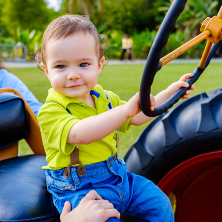 Cute baby boy riding a farm tractor.の写真素材