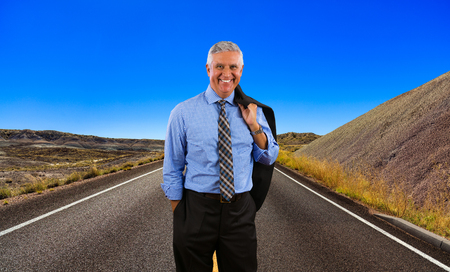 Handsome middle age business man standing on a desert highway.の写真素材