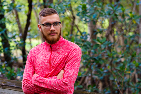 Handsome young man with a beard in a outdoor park setting.