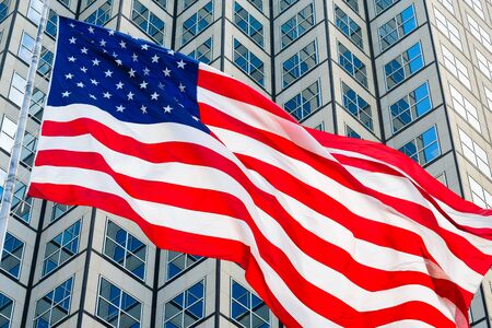 Close up view of a American flag flying in the wind with a downtown skyscraper background.の写真素材