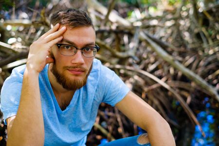 Handsome young man with a beard in a outdoor park setting.の写真素材
