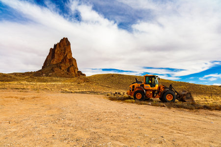 Navajo County, AZ USA - November 1, 2016: Backhoe preparing to excavate with the beautiful Agathla Peak butte in the background.のeditorial素材