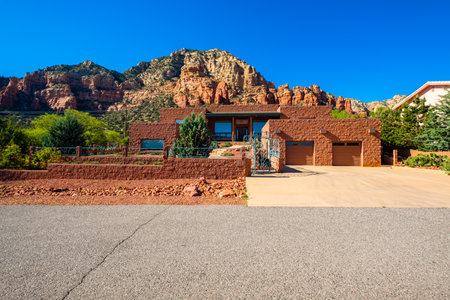 Sedona, Arizona USA - April 25, 2017: Typical modern adobe style architecture desert home with majestic red rock formations in the background in popular Sedona.のeditorial素材