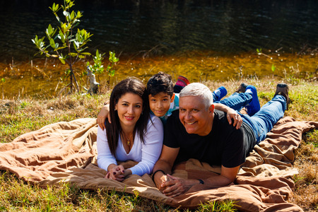 Mother, Father and son outdoor lifestyle portrait in a park setting.