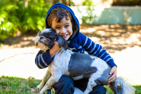 Cute boy enjoying the outdoors in a home yard setting with his dog.の写真素材