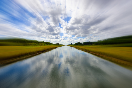 Long canal along a rural area on a cloudy day with a blurred effect.の写真素材