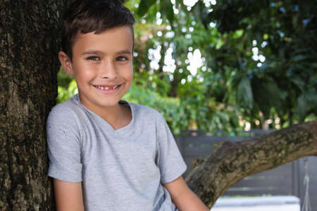 Cute boy enjoying the outdoors sitting in a tree.