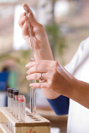 Woman pours a drop of liquid in a glass flask