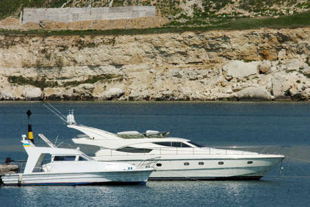 two boats floating on the sea against the rocksの写真素材