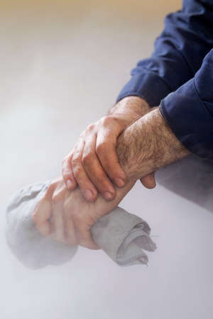 working hand that holds the cloth amid the smoke