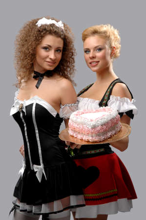Two pretty waitress with a large cake with creamの写真素材