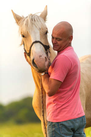 Photo bald man walks with a horse in the fieldの写真素材