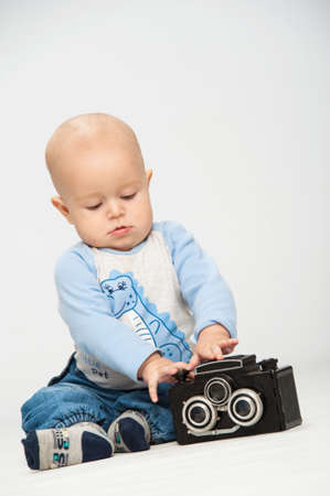 Photo of a little boy holding an old film cameraの写真素材