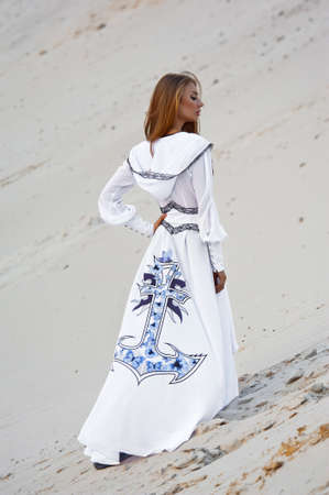 Photo of a beautiful and charming girl on the beach in clothesの写真素材